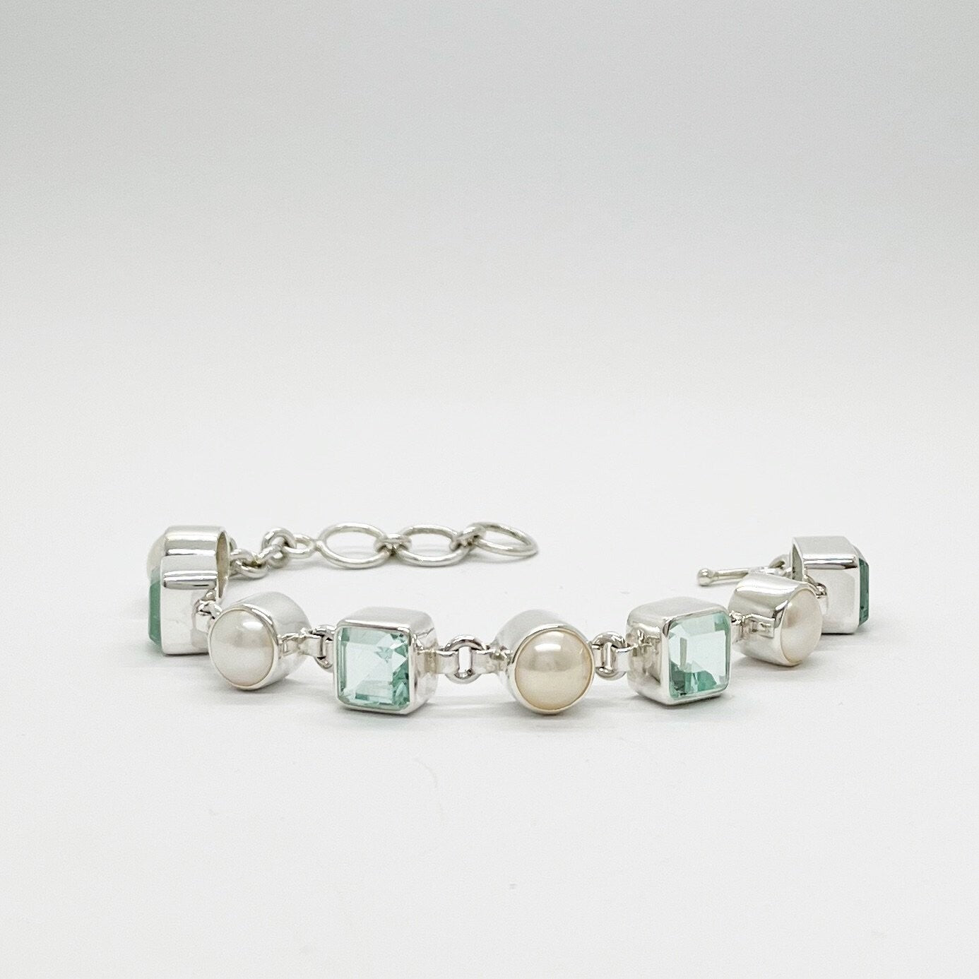 Meeresblaues Armband aus 925er Silber mit Perlen und quadratischen aquamarinfarbenen Steinen.