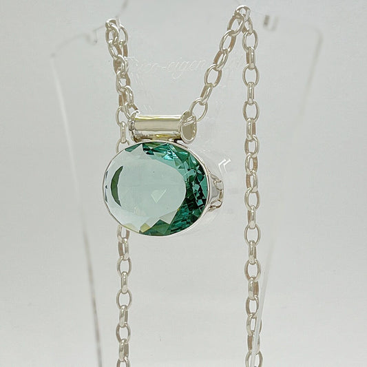 Silberanhänger mit ovalem meerblauem Obsidian, facettierter Stein, 3,5 × 4,5 cm, an Silberkette.