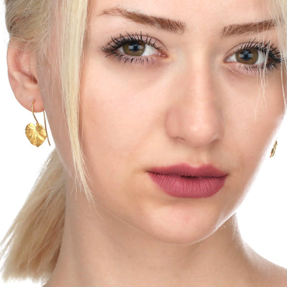 Vergoldete Silber Ohrringe im tropischen Blatt-Design (Monstera-Blatt) am Ohr einer Frau.