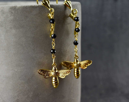 Goldene Bienen-Ohrringe mit schwarzem Onyx, filigrane Ketten mit facettierten Onyx-Kugeln.