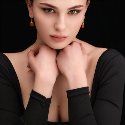 Frau trägt vergoldete 925er Silber Ohrringe mit Karneol-Tropfen in Orange.