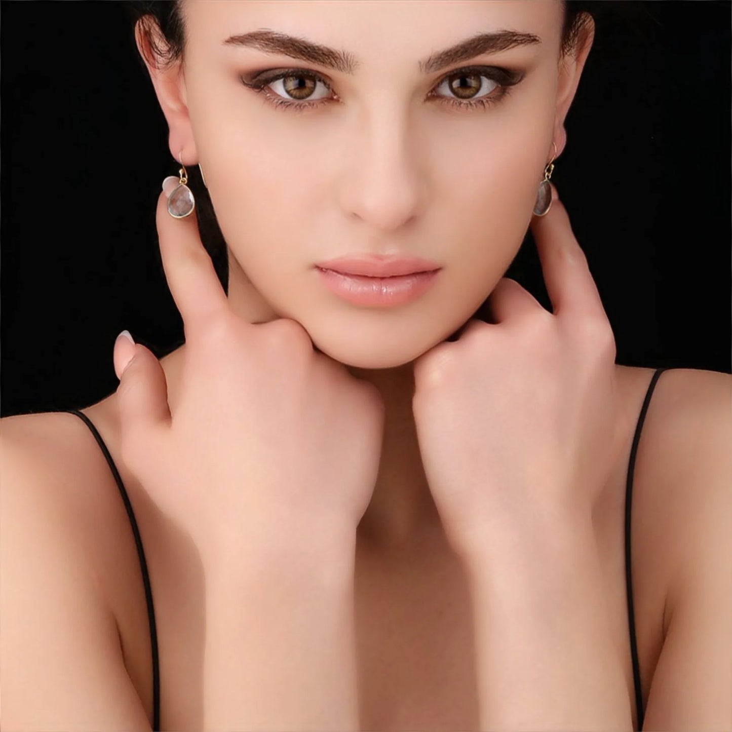 Modell trägt vergoldete 925 Silber Ohrringe mit Aqua Topas – blau schimmernde Edelsteine