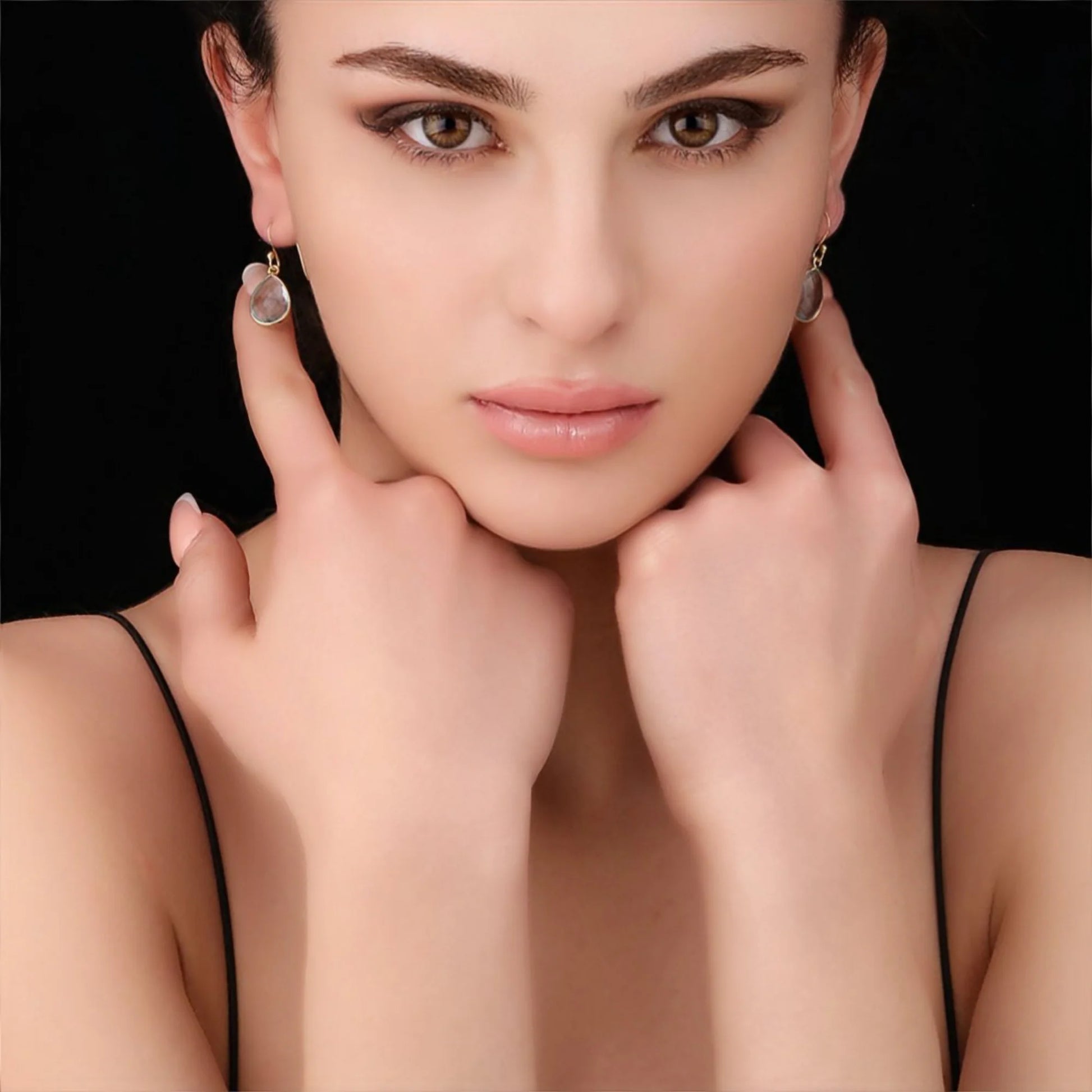 Modell trägt vergoldete 925 Silber Ohrringe mit Aqua Topas – blau schimmernde Edelsteine